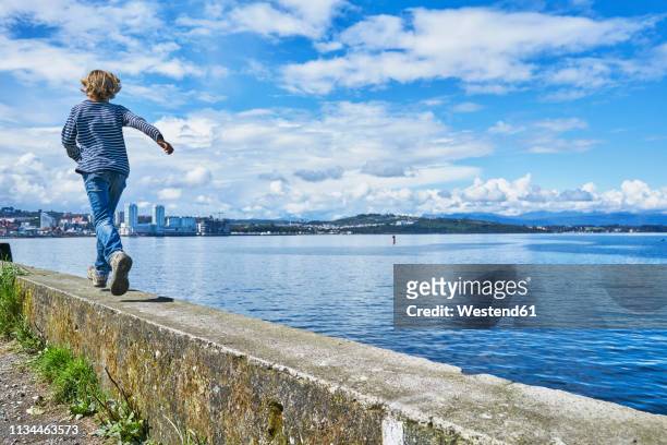 chile, puerto montt, boy running on quay wall at the harbor - puerto montt 個照片及圖片檔