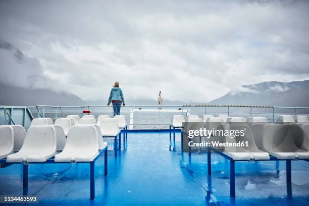 chile, hornopiren, woman standing at rail of a ferry looking at fjord - ferry passenger stock pictures, royalty-free photos & images