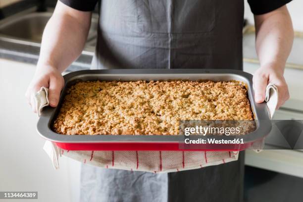man in kitchen holding baking tray with homemade rhubarb cake, partial view - blechkuchen stock-fotos und bilder