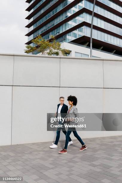 two happy colleagues walking outside office building - farewell colleague stock pictures, royalty-free photos & images