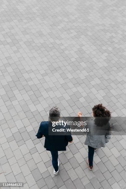 top view of two colleagues walking on a square - people aerial view stockfoto's en -beelden