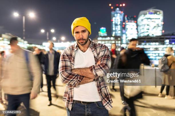 uk, london, portrait of a commuter by night with blurred people passing nearby - standing out from the crowd (expressão inglesa) imagens e fotografias de stock