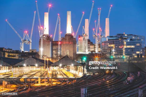 united kingdom, england, london, view of railtracks and trains in the evening, former battersea power station and cranes in the background - battersea power station stockfoto's en -beelden