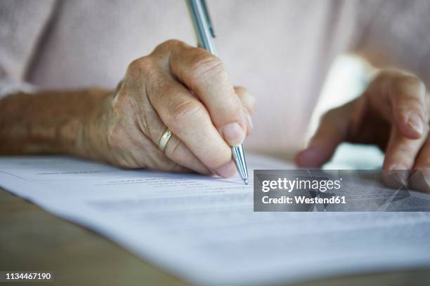 senior woman's hand signing a document, close-up - erfenis stockfoto's en -beelden