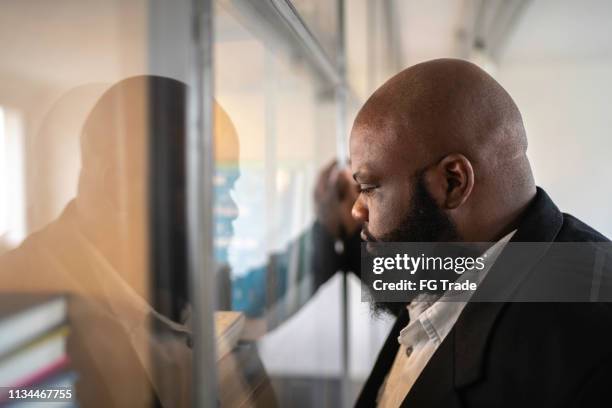 afrikanische ethnizität geschäftsmann fühlt sich schlecht in der nähe des fensters - kündigungsfrist stock-fotos und bilder