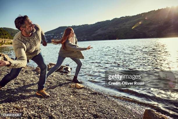 father and adult daughter skipping stones on a river - skimming stones stock pictures, royalty-free photos & images