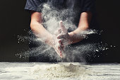 Clap hands of baker with flour in kitchen