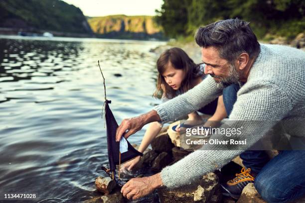 father and daughter starting self-built model boat on a river - spielzeugschiff stock-fotos und bilder