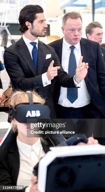 April 2019, Lower Saxony, Hannover: Carl Philip , Prince of Sweden, and Frank Duggan, Head of Global Markets at ABB, chat at the company's booth at...
