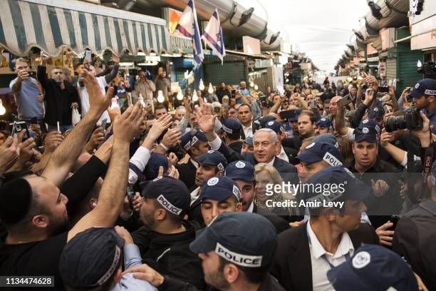 Israeli Prime Minster Benjamin Netanyahu and his wife Sara Netanyahu gesture to supporters as they visit Tel Aviv's vegetable market Hatikva on April...