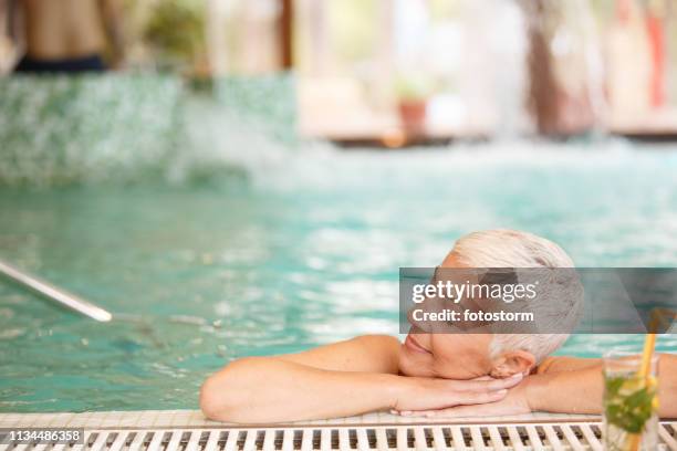 mujer madura relajante en la piscina - balneario fotografías e imágenes de stock