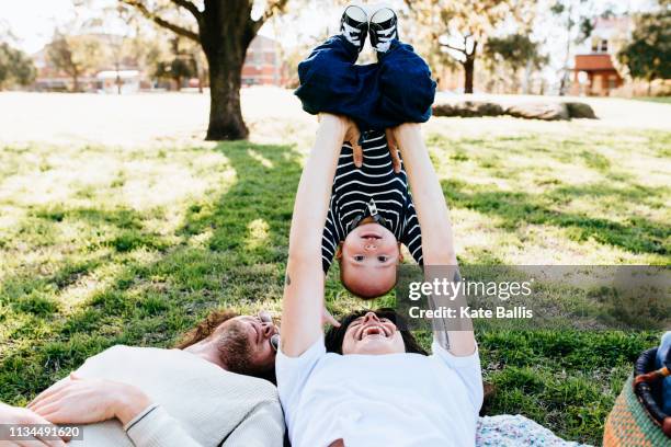 couple with baby on picnic blanket in park - baby light stock-fotos und bilder