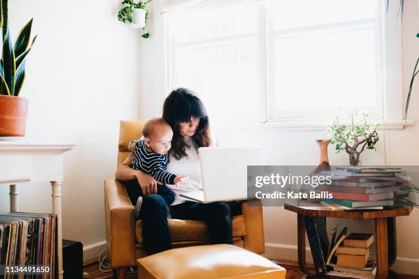 mother using laptop with son on lap - hipster australia stock pictures, royalty-free photos & images