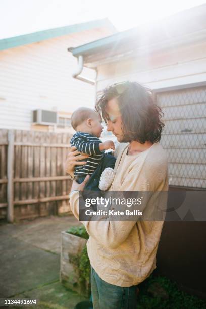 father with son in arms beside house - hipster australia stock pictures, royalty-free photos & images