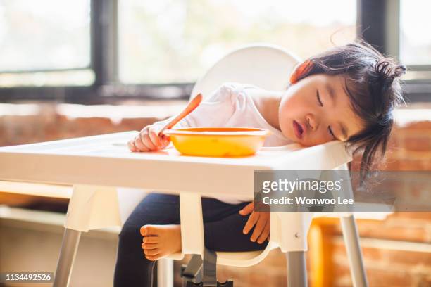 one year old baby girl asleep in highchair at breakfast - candidates for time person of the year 2014 stockfoto's en -beelden