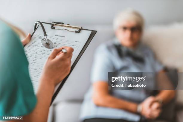 health visitor and senior man during home visit. - nursing home interior stock pictures, royalty-free photos & images