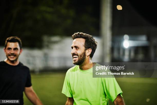 male soccer player laughing with friends during evening game - two guys playing soccer stockfoto's en -beelden