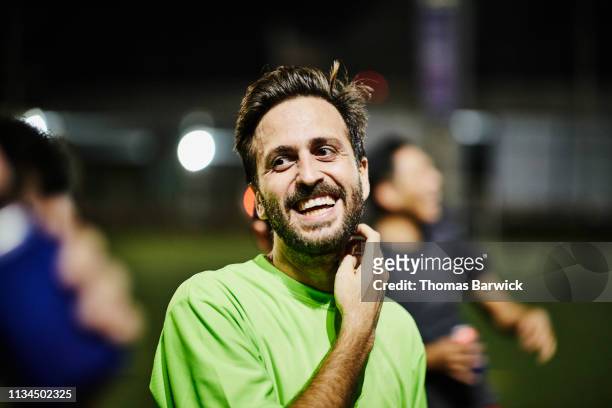 laughing male soccer player hanging out with friends after nighttime soccer game - soccer men stock-fotos und bilder