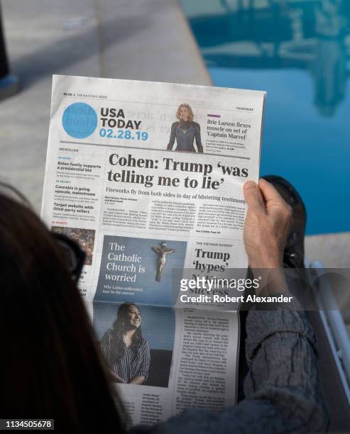 Woman relaxing beside a hotel swimming pool in Palm Springs, California, reads a copy of USA today with a headline and front page news article on...