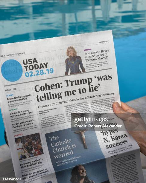 Woman relaxing beside a hotel swimming pool in Palm Springs, California, reads a copy of USA today with a headline and front page news article on...