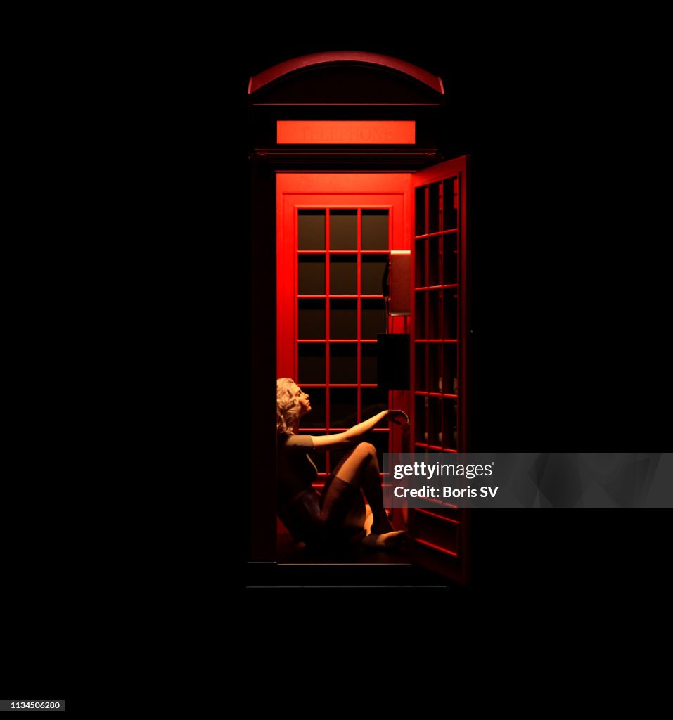 Woman waiting in red phone booth