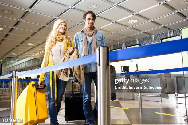 couple rolling luggage in airport - departure board front on fotografías e imágenes de stock