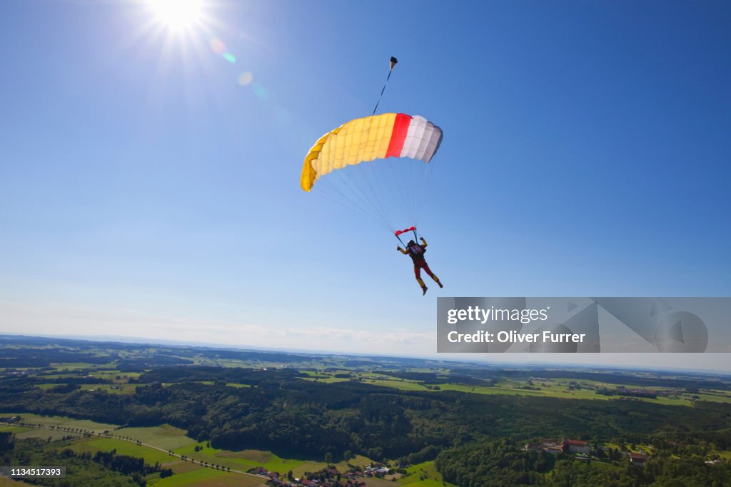 Man parachuting over rural landscape