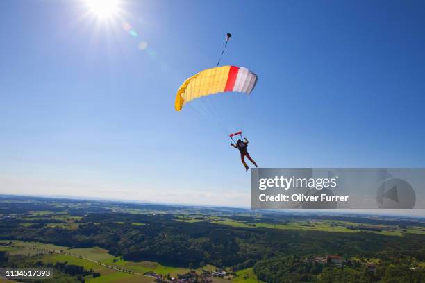 man parachuting over rural landscape - skydiving photos et images de collection