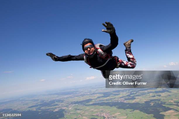 man skydiving over rural landscape - paracaídas fotografías e imágenes de stock
