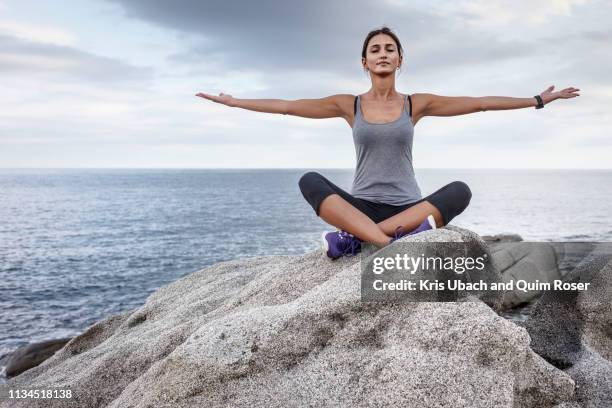 woman meditating on boulder - woman with arms outstretched stock pictures, royalty-free photos & images