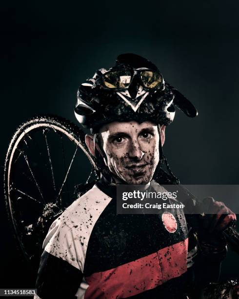 mud splattered cyclist carrying bicycle - muddy bike studio stock-fotos und bilder