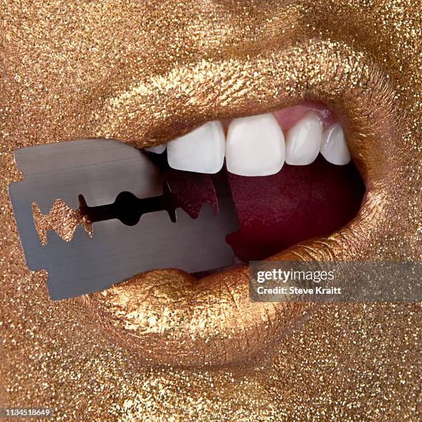 woman in gold holding razor in mouth - zahn gold stock-fotos und bilder