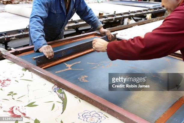 two men screen printing in textiles factory - textile printing foto e immagini stock