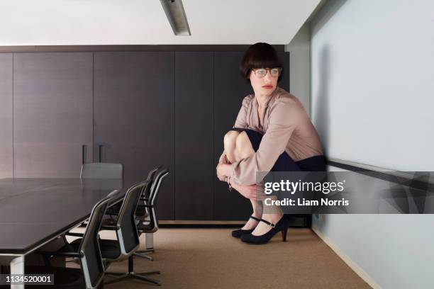 businesswoman crouching in small conference room - woman stuck stock pictures, royalty-free photos & images