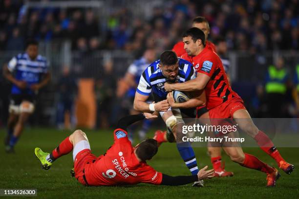 Elliott Stooke of Bath is tackled by Ben Spencer and Alex Lozowski of Saracens during the Gallagher Premiership Rugby match between Bath Rugby and...