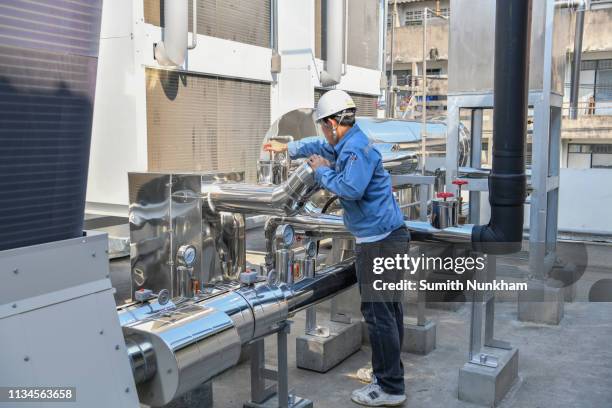 engineer tuning valve of flow rate and checking temperature on pressure gauge of cooling water system in the factory - chillar stock pictures, royalty-free photos & images