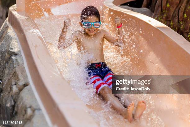 happy child använda vatten glida in i poolen - waterslide bildbanksfoton och bilder