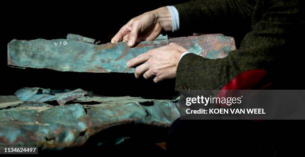 This picture taken on April 3, 2019 shows copper plates from a ship wreck from 1536 that was discovered during the storage of the containers that...