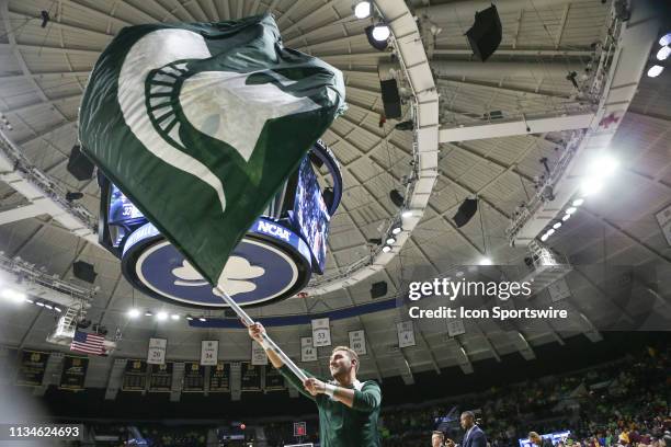 Michigan State cheerleader waves the team flag during the NCAA Division I Women's Championship First Round basketball game between the Central...