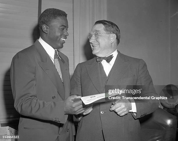 Jackie Robinson and Branch Rickey talk happily after a contract signing meeting in the offices of the Brooklyn Dodgers in Ebbets Field in...