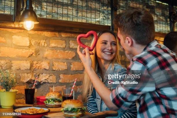 couple holding heart shaped bagel - valentines day dinner stock pictures, royalty-free photos & images