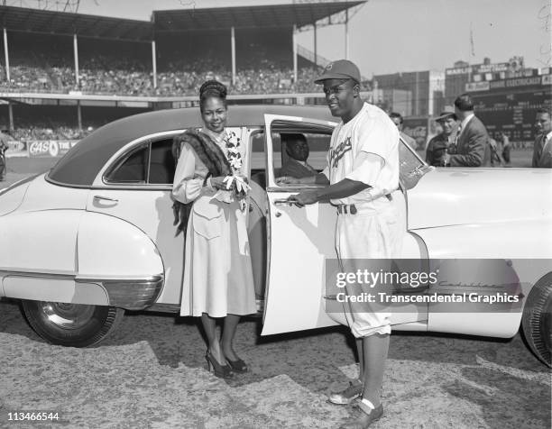 Jackie Robinson and his wife pose for photographs after a special awards ceremony in Ebbets Field, where Robinson was given a new car on Jackie...