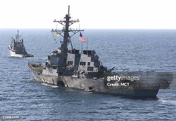 The U.S. Navy destroyer USS Cole is towed away from the port city of Aden, Yemen, into open sea by the Military Sealift Command ocean-going tug USNS...