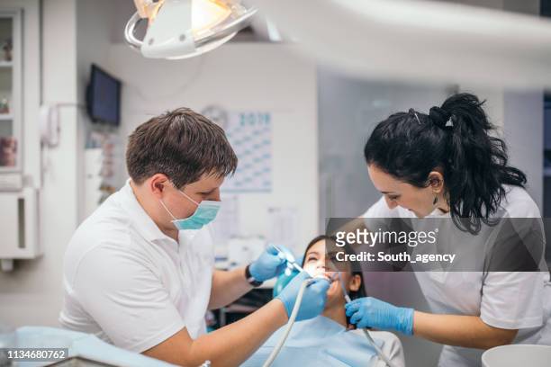 zahnarzt und patient in der zahnarztpraxis - sprechstundenhilfe stock-fotos und bilder