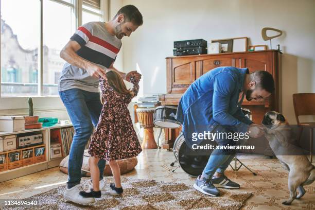 Gay couple dancing with daughter and pug at home