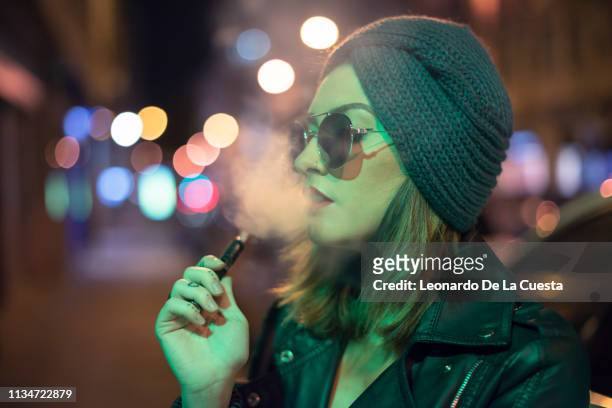 young woman smokes electronic cigarette. - electronic cigarette stock pictures, royalty-free photos & images