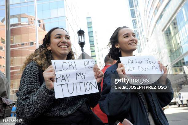 Mackenzie Thomas and Vivi Bonomie hold signs while actress Lori Loughlin faces charges for allegedly conspiring to commit mail fraud and other...