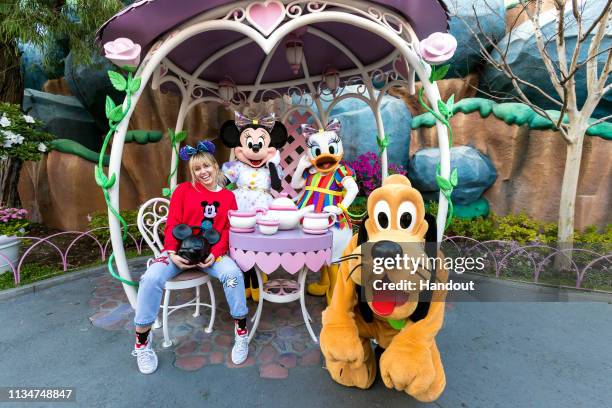 In this handout photo provided by Disneyland Resort, Musician Miley Cyrus poses with Minnie Mouse, Daisy Duck and Pluto during Get Your Ears On - A...
