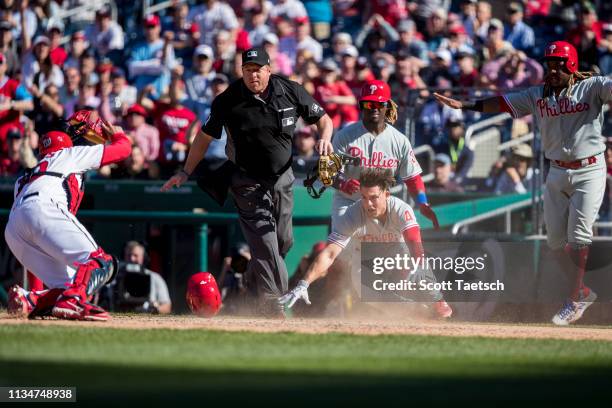 April 03: Scott Kingery of the Philadelphia Phillies beats the tag by Kurt Suzuki of the Washington Nationals to score during the eighth inning at...