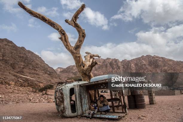 Picture taken on March 30 shows Egyptian Bedouin children sitting in a rusted shell of a truck in the village of al-Hamada in Wadi el-Sahu in South...